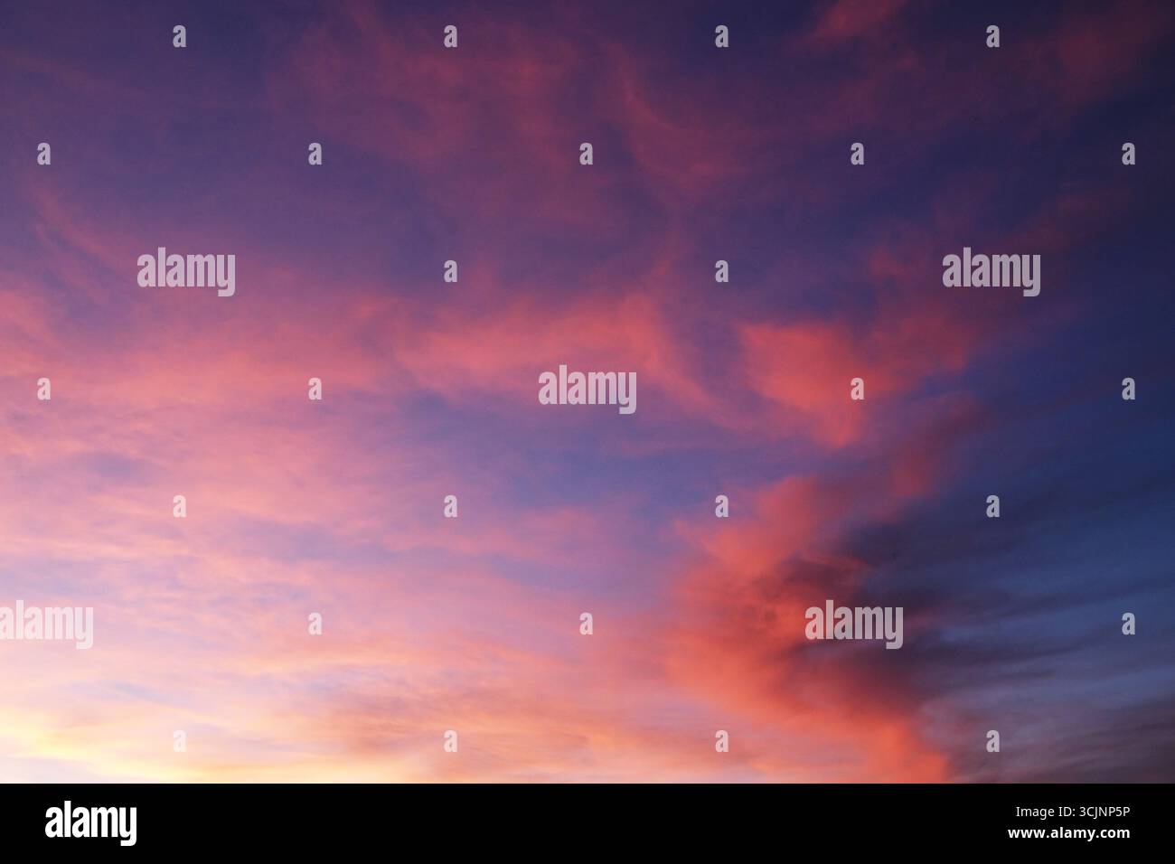 Himmel bei Sonnenuntergang mit rosa, orangen, lila, blauen und türkisfarbenen Wolken und violetten Tönen Stockfoto