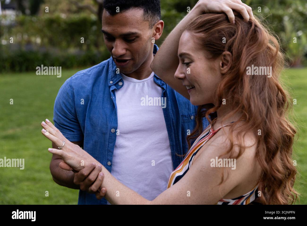Junges Paar feiert Verlobung im Park, bewundert Ring vor Freude Stockfoto