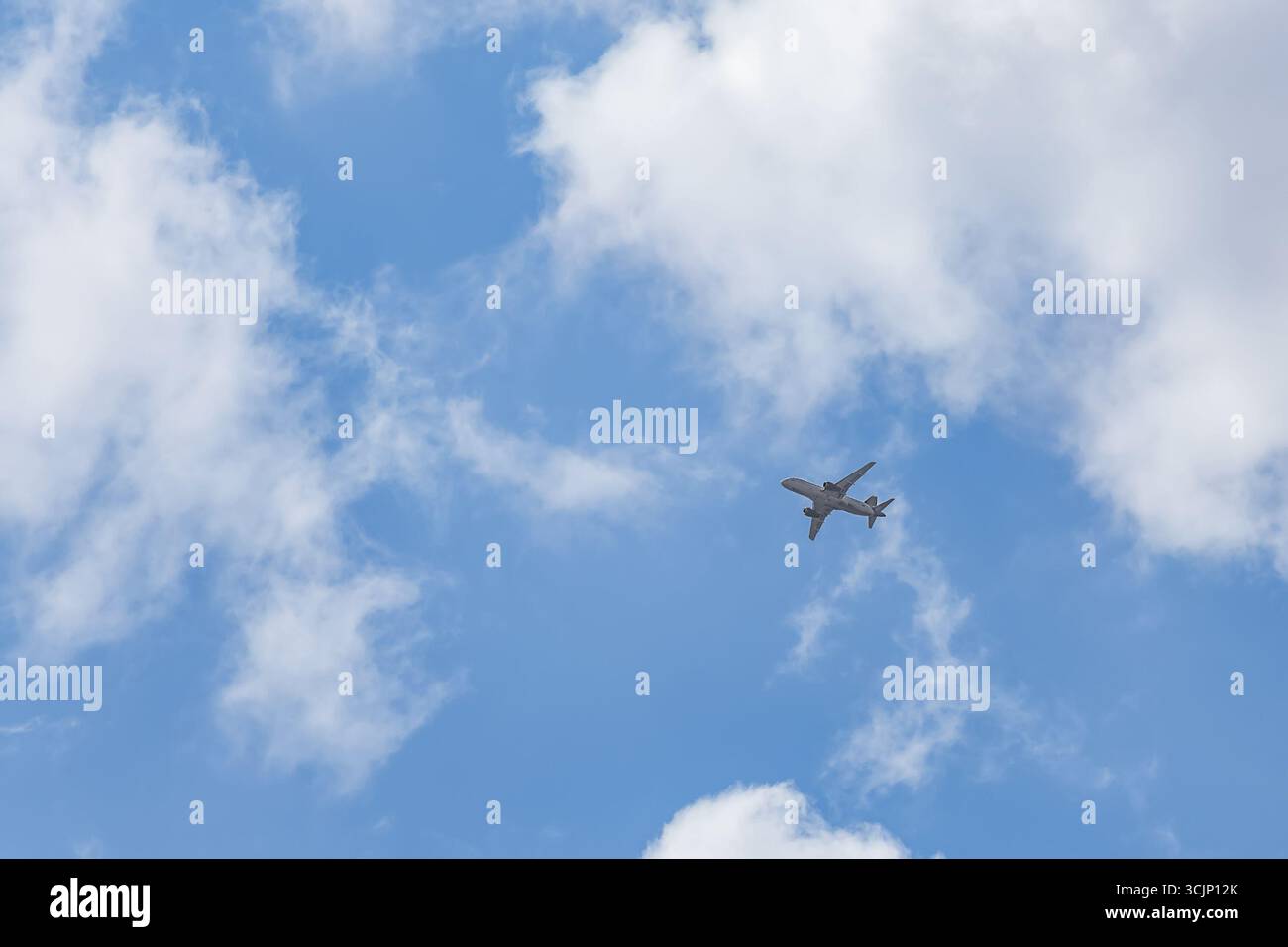 Ein Flugzeug fliegt über dem Himmel vor einem blauen Himmel mit dünnen Wolken. Stockfoto