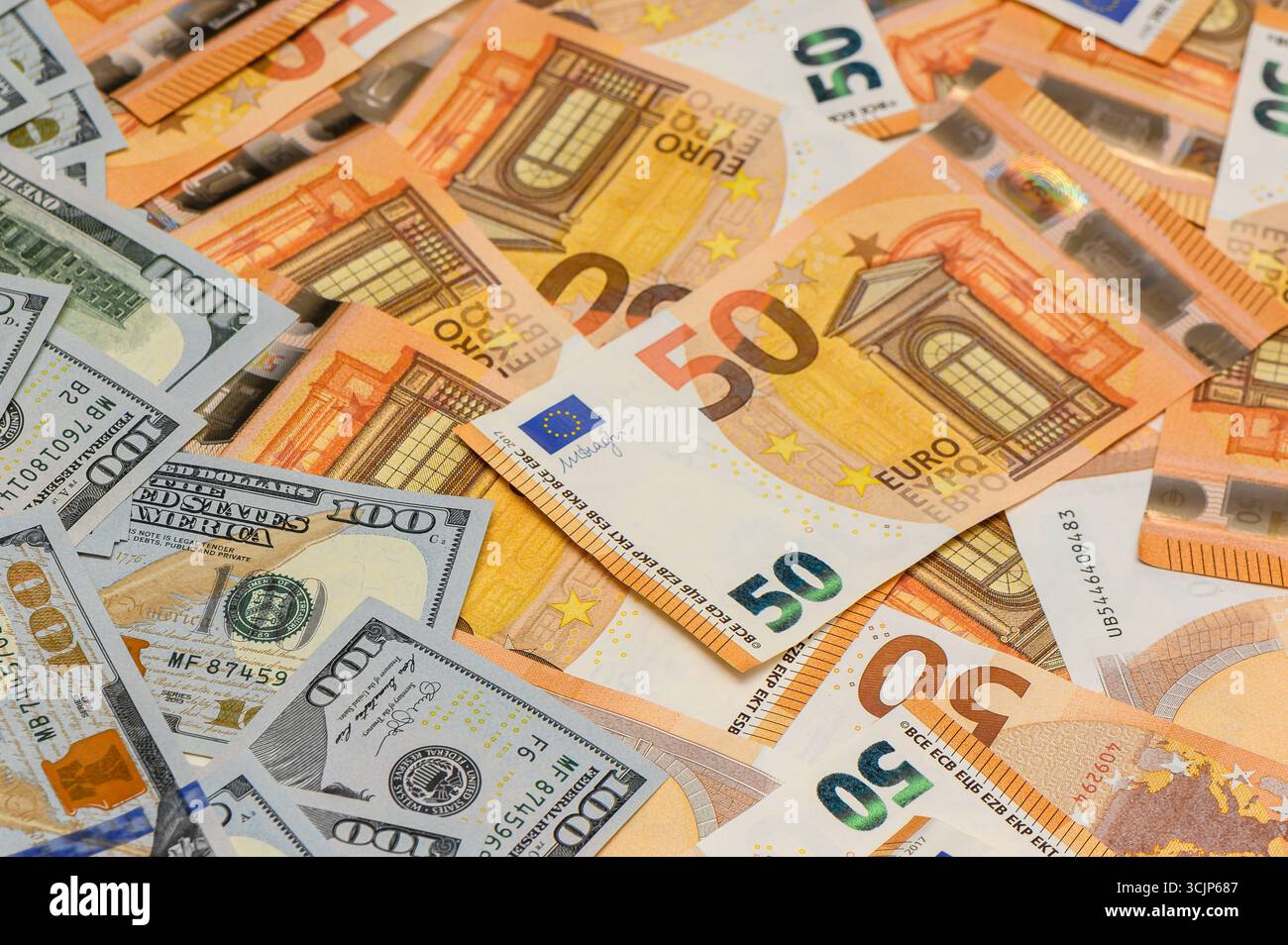 Makroansicht von 100 US-Dollar-Scheinen und 50 Euro-Banknoten auf dem Tisch, die einen strukturierten Geldhintergrund für die finanzielle und wirtschaftliche Nutzung bilden. Stockfoto