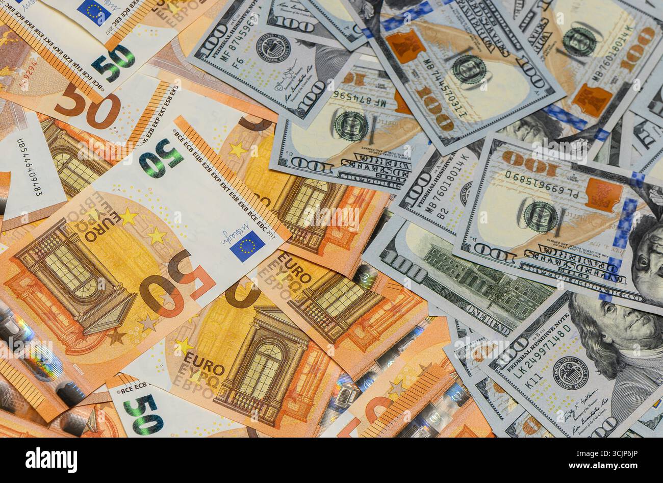 Gemischte 100 US-Dollar-Scheine und 50 Euro-Scheine auf einem Tisch, wodurch ein Finanz- und Vermögenshintergrund entsteht. Stockfoto