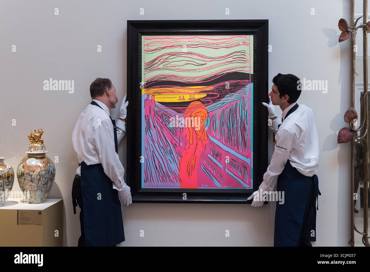 LONDON, VEREINIGTES KÖNIGREICH - 8. SEPTEMBER 2025: Kunstschaffende halten „The Scream (After Munch)“ von Andy Warhol, Schätzung: £ 2.000.000 - 3.000.000 während eines Fotoanrufs in Sotheby's Auktionshaus für die Ausstellung „Pauline Karpidas: The London Collection“ und Verkauf in London, Vereinigtes Königreich am 8. September 2025. Die außergewöhnliche persönliche Sammlung der legendären Mäzene und Ästhetik Pauline Karpidas, in der Meisterwerke surrealistischer Kunst und Möbeldesign zu sehen sind, die ihr einzigartiges Zuhause in London schmückten, wird am 17. Und 18. September im Sotheby's angeboten, zusammen auf über £60 Mio. geschätzt Stockfoto