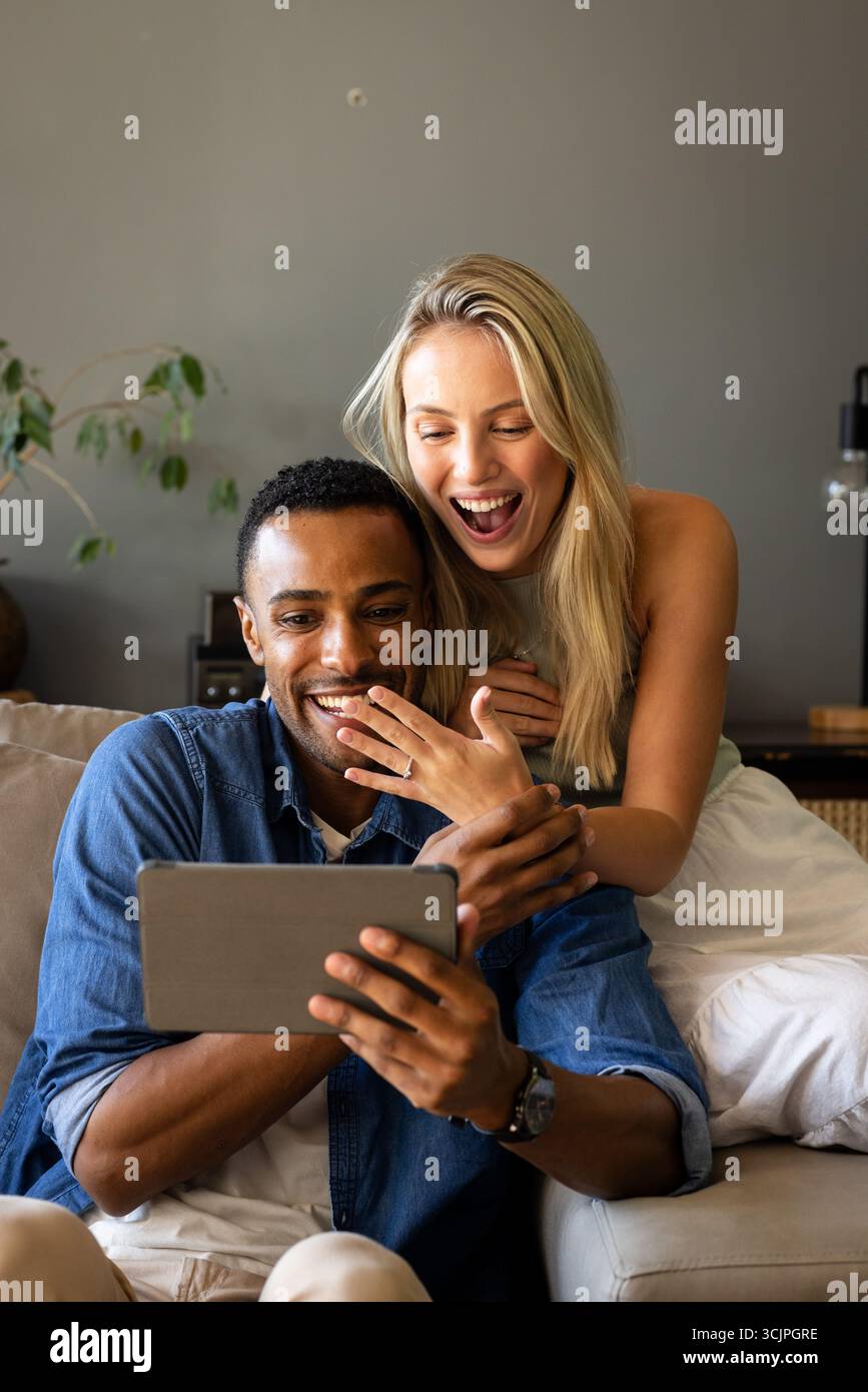 Paare sitzen auf der Couch und schauen sich ein Tablet an, um gemeinsam spannende Momente zu teilen Stockfoto