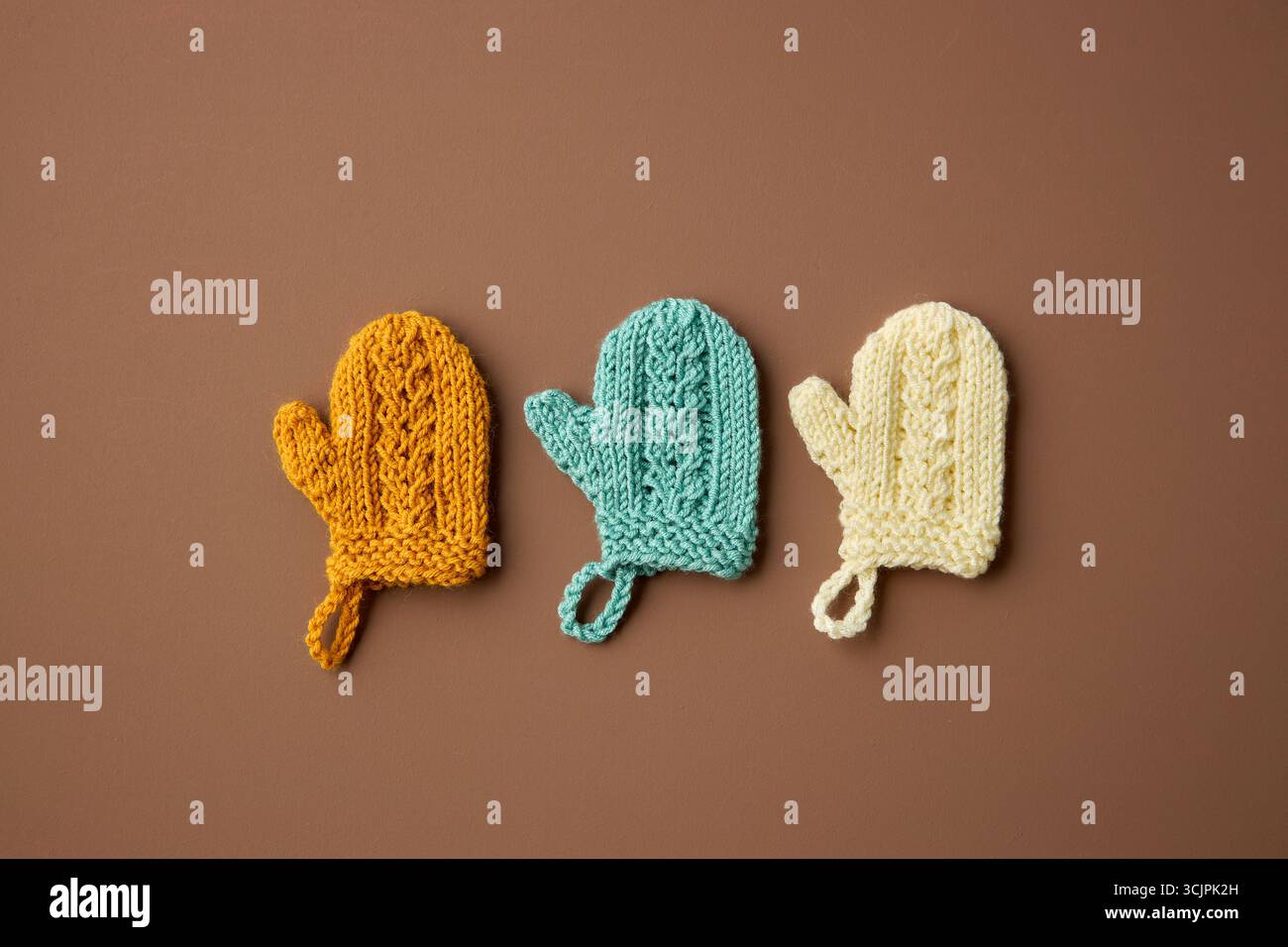 Mini-Handschuhe Handgestrickt. Weihnachtsbaumschmuck. Minimaler Winterhintergrund. Flache Lagen. Stockfoto