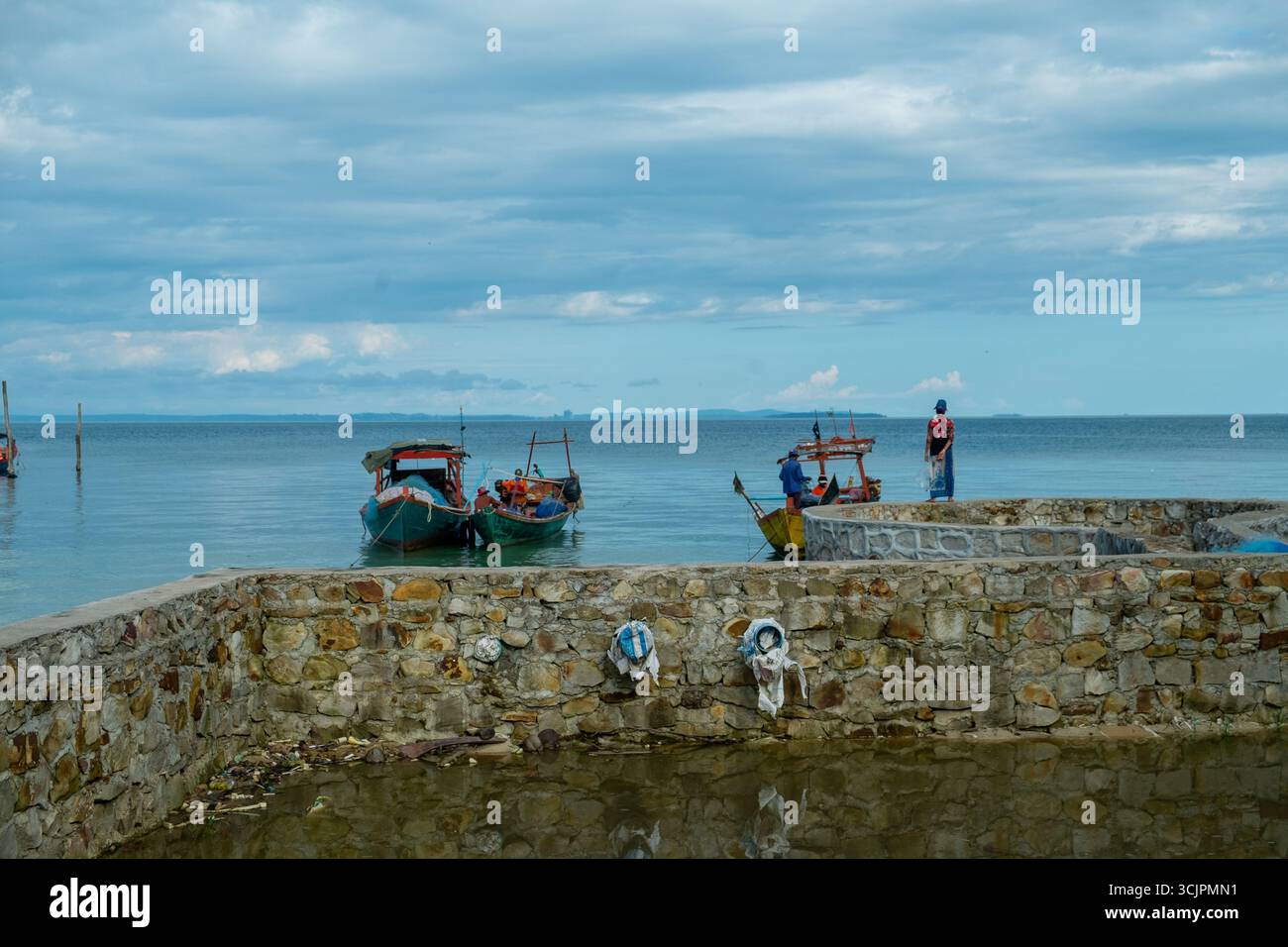 Fischer auf einem Steinpier mit Booten in Koh Rong, Kambodscha. 2018 Stockfoto