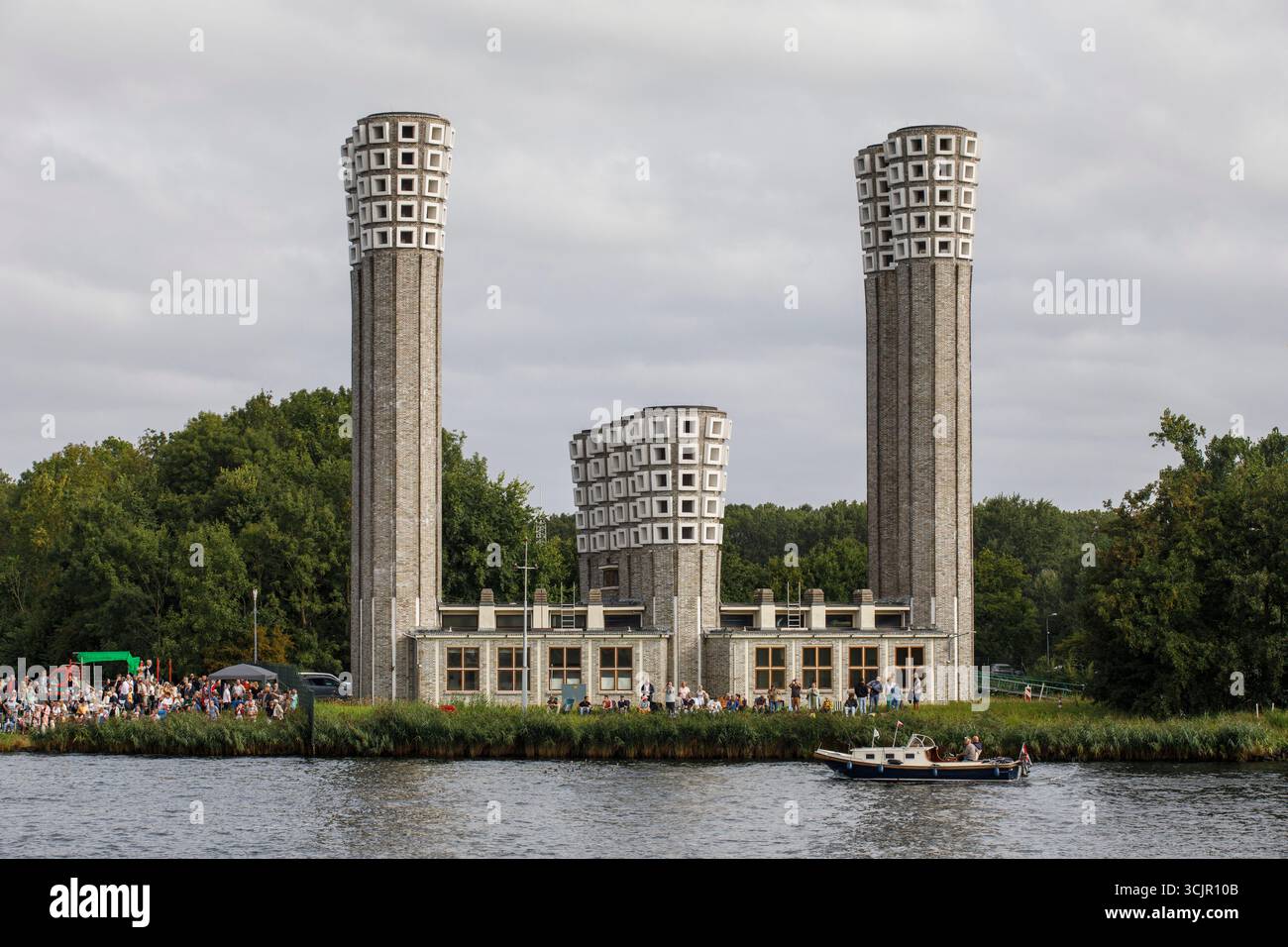Segel-in-Parade des Sail Amsterdam, 20. August 2025, passiert ein kleines Boot die Lüftungstürme des Velser-Tunnels, Niederlande. Die Segel Amsterda Stockfoto