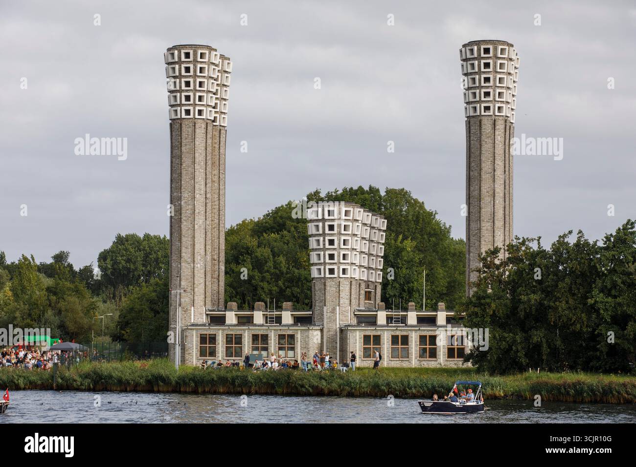 Segel-in-Parade des Sail Amsterdam, 20. August 2025, passiert ein kleines Boot die Lüftungstürme des Velser-Tunnels, Niederlande. Die Segel Amsterda Stockfoto