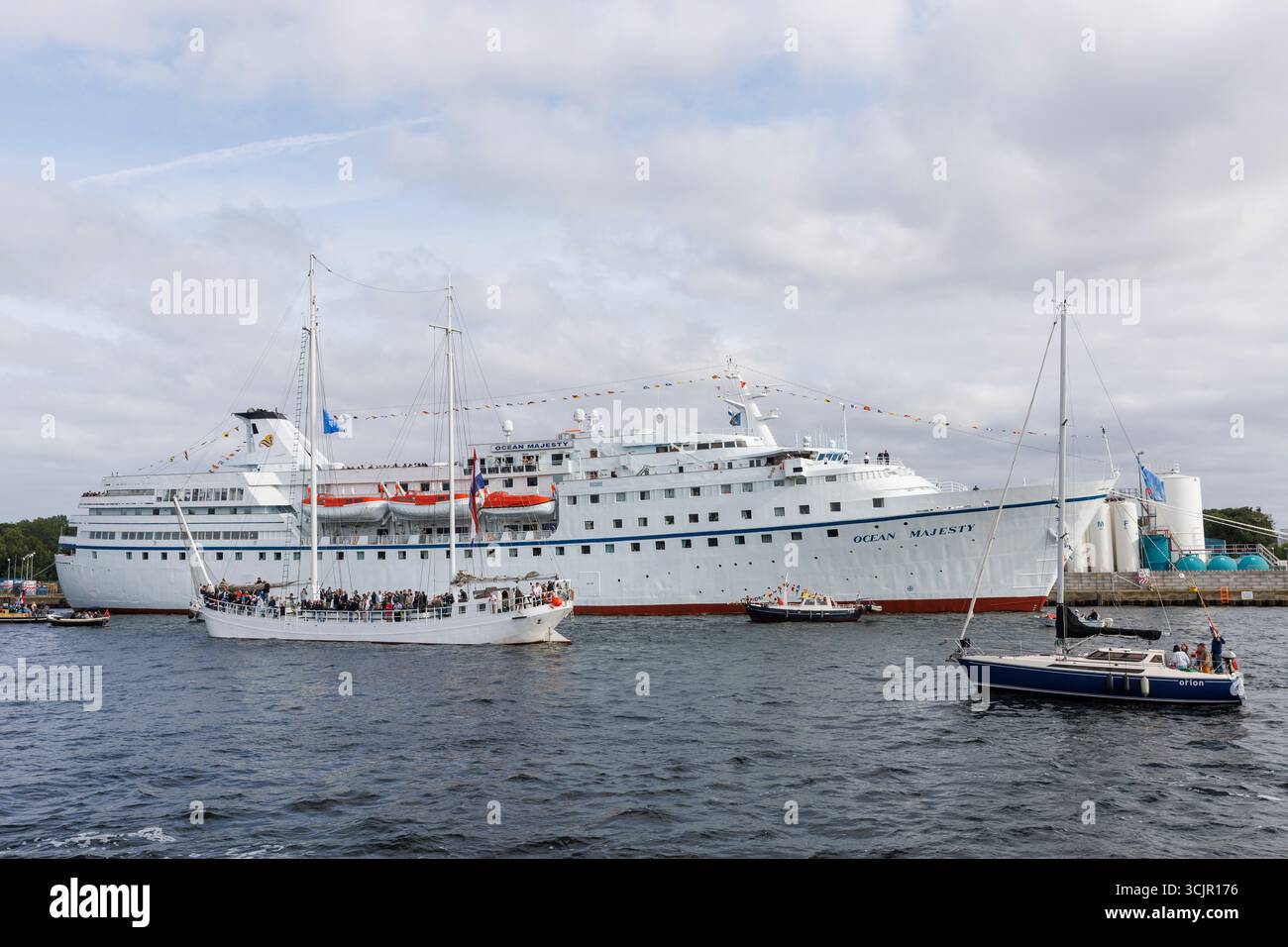 Segel-in-Parade der Sail Amsterdam, 20. August 2025, passiert ein zwei-Meister das ehemalige Kreuzfahrtschiff Ocean Majesty, das heute als Flüchtlingsunterkunft genutzt wird, ne Stockfoto