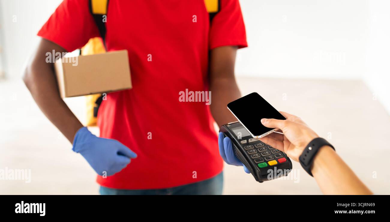 Schwarzer Mann mit POS-Maschine-Client, der mit Smartphone bezahlt Stockfoto
