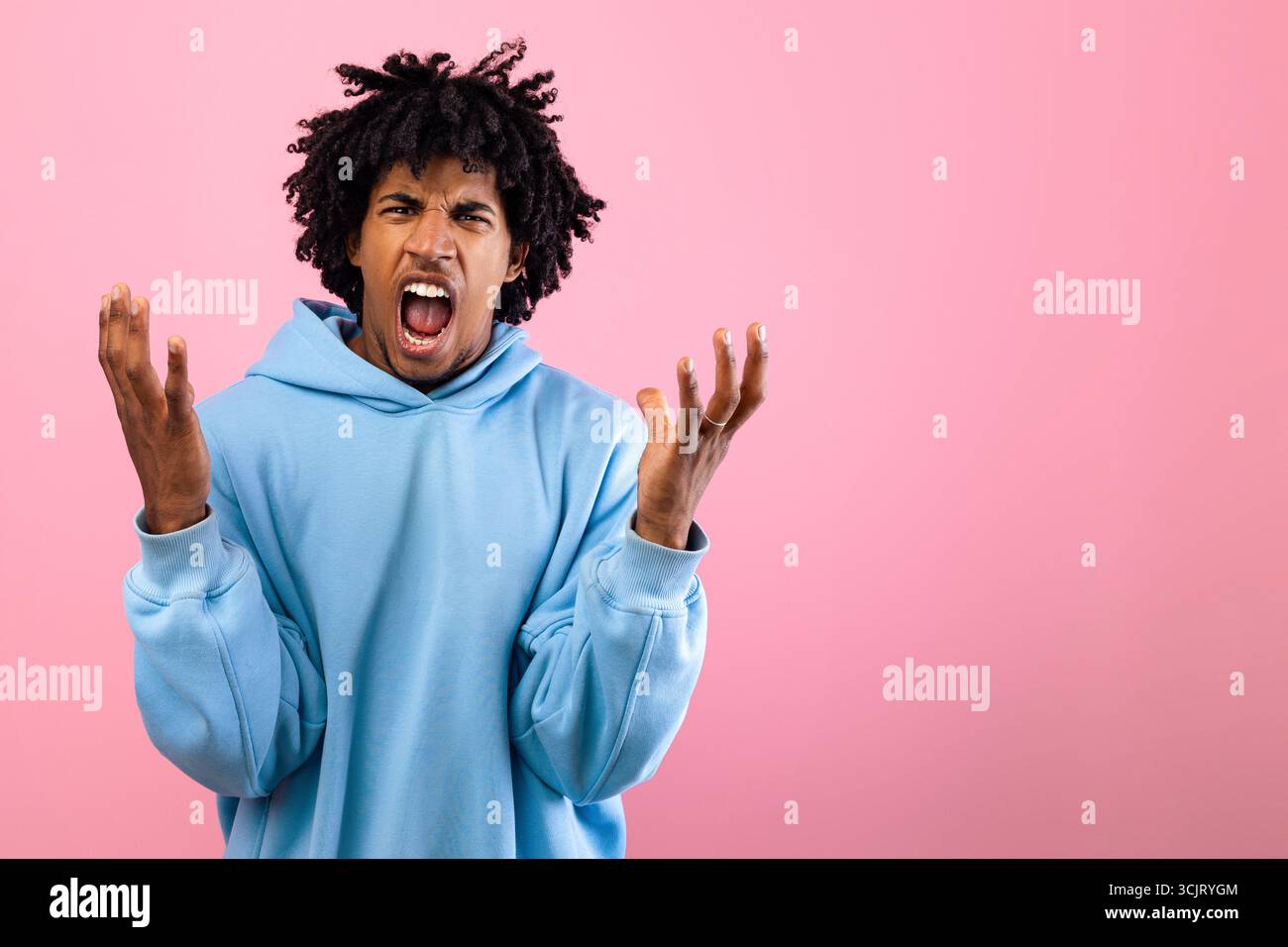 Wütender schwarzer Teenager, der vor Wut auf rosafarbenem Studiohintergrund schreit Stockfoto
