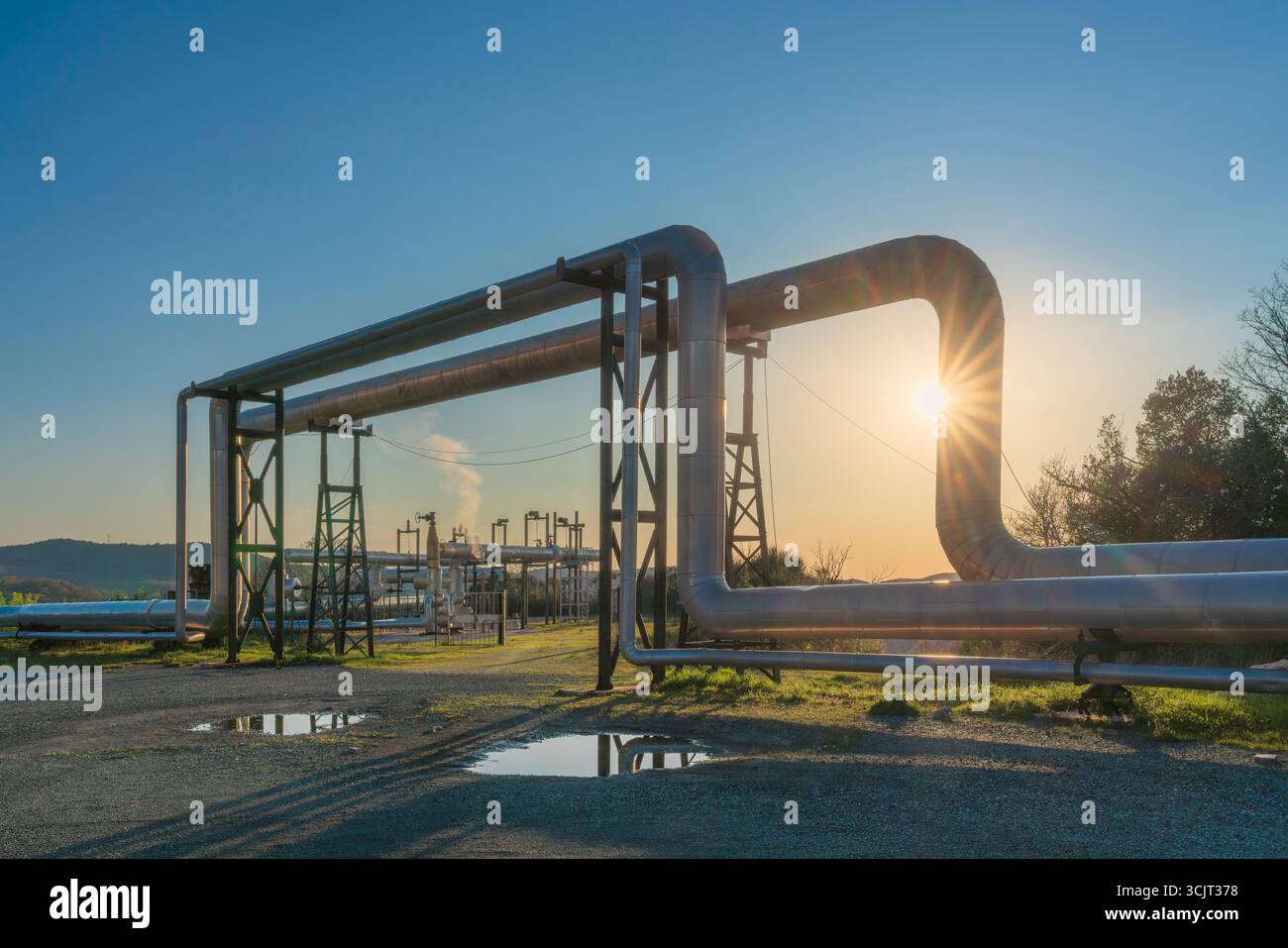Pipelines eines geothermischen Kraftwerks bei Sonnenuntergang in Larderello, Toskana, Italien. Geothermie ist eine Form alternativer und nachhaltiger Energie Stockfoto