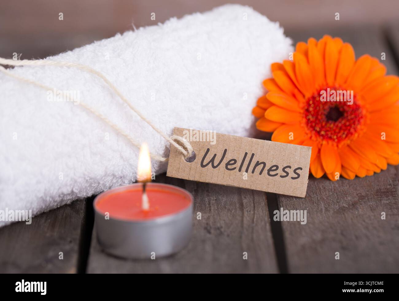 Orange Blume, Handtuch, Teelicht und Pappschild?Wellness? Stockfoto