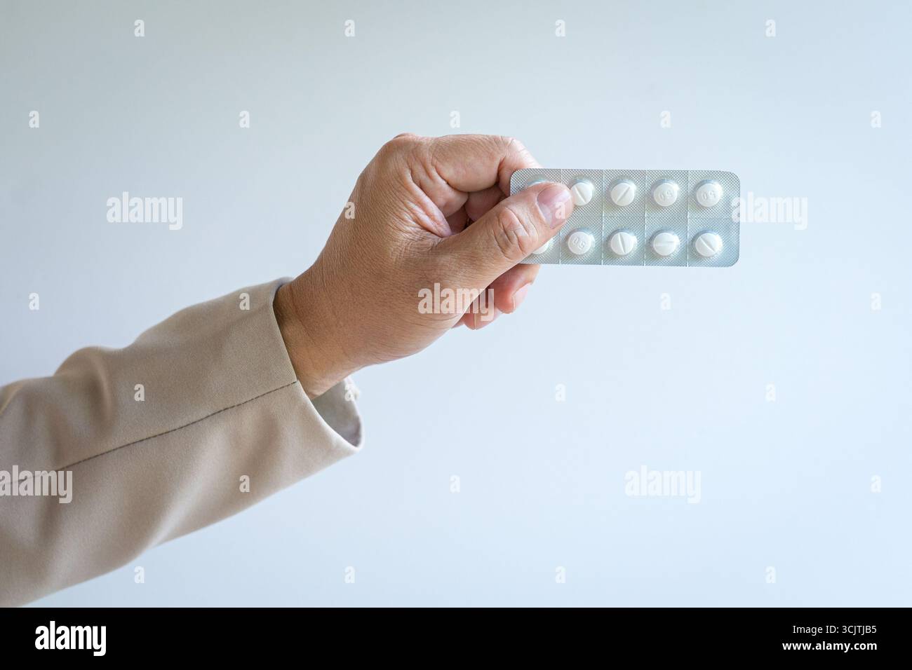 Mann, der einen Tablettenstreifen hält. Isoliert auf weißem Hintergrund, Nahansicht. Stockfoto