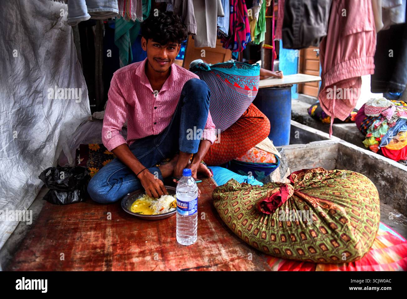 Mumbai, Indien. September 2025. Ein Arbeiter nimmt sein Mittagessen in Dhobi Ghat, einer großen Open-Air-Wäscherei in Mumbai, Indien. Dhobi Ghat, ein Freiluft-Waschraum mit Wohn- und Geschäftsgebäuden im Hintergrund in der Mahalaxmi-Gegend von Mumbai, Indien (Foto: Avishek das/SOPA Images/SIPA USA) Credit: SIPA USA/Alamy Live News Stockfoto