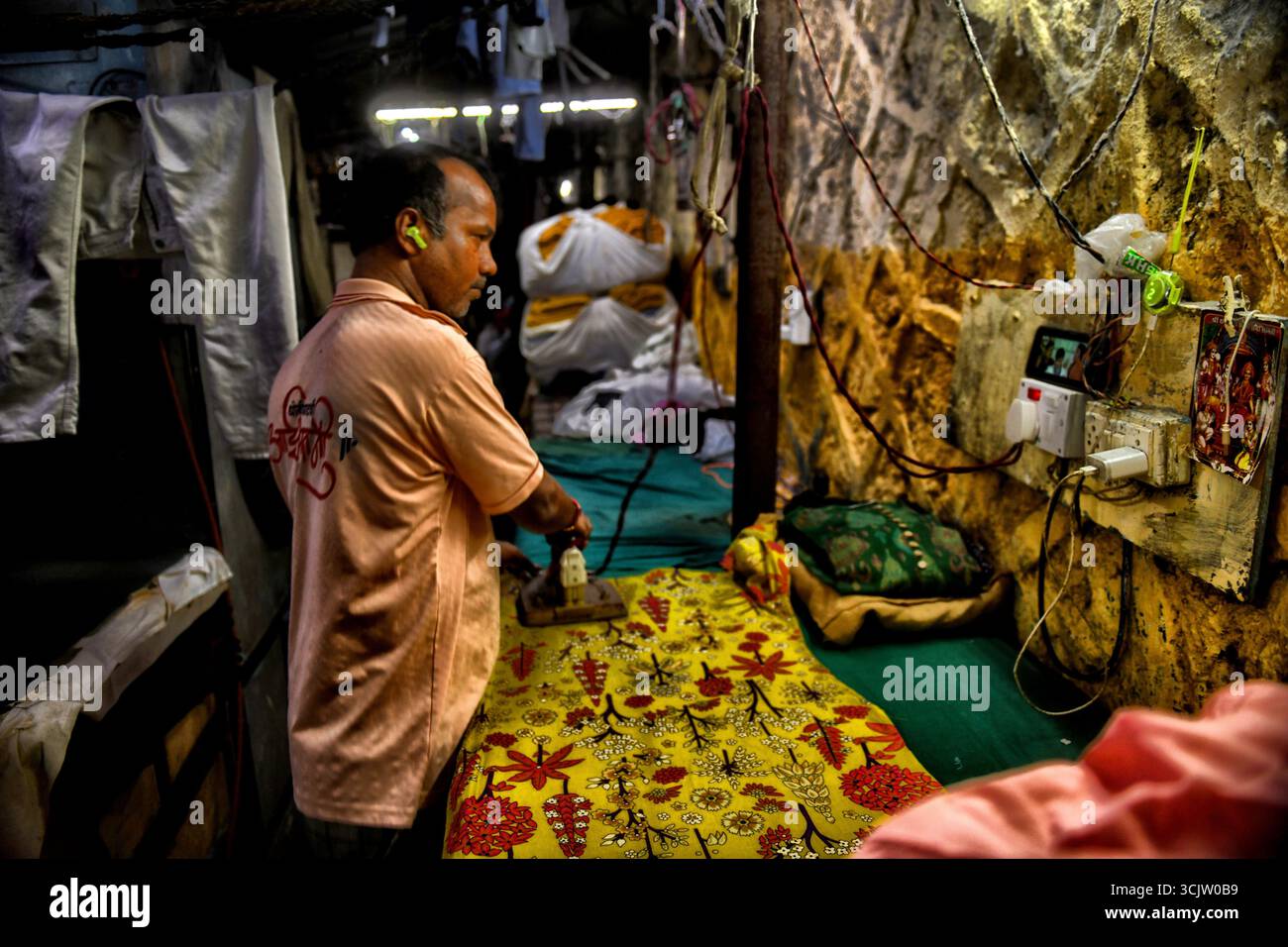 Mumbai, Indien. September 2025. Ein Arbeiter bügelt Kleidung in einer Open-Air-Wäscherei, bekannt als Dhobi Ghat in Mumbai. Dhobi Ghat, ein Freiluft-Waschraum mit Wohn- und Geschäftsgebäuden im Hintergrund in der Mahalaxmi-Gegend von Mumbai, Indien (Foto: Avishek das/SOPA Images/SIPA USA) Credit: SIPA USA/Alamy Live News Stockfoto