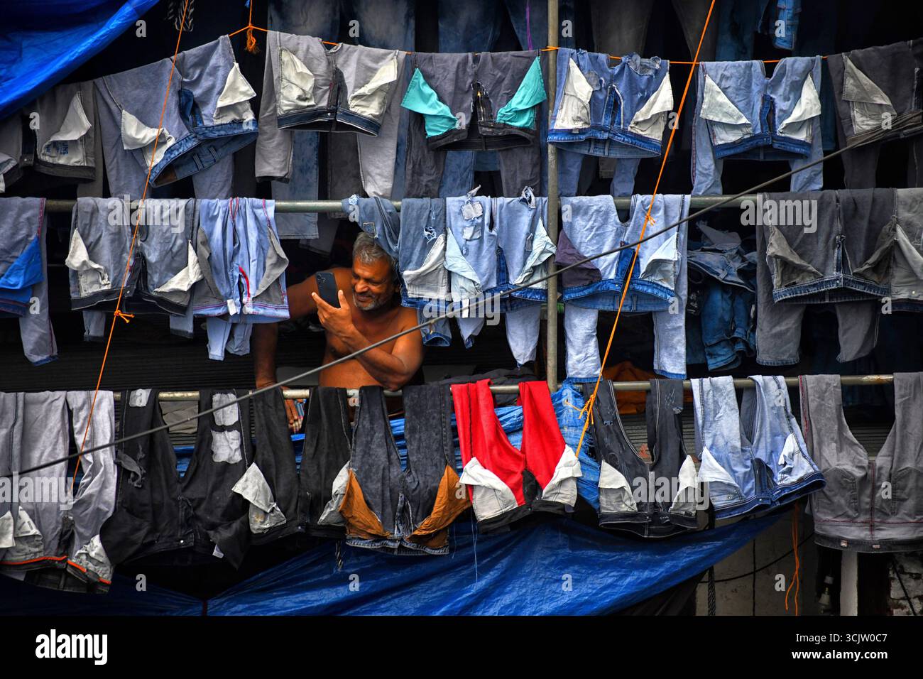 Mumbai, Indien. September 2025. Ein Arbeiter tätigt mobile Videoanrufe von seinem Wohnsitz in Dhobi Ghat in Mumbai. Dhobi Ghat, ein Freiluft-Waschraum mit Wohn- und Geschäftsgebäuden im Hintergrund in der Mahalaxmi-Gegend von Mumbai, Indien (Foto: Avishek das/SOPA Images/SIPA USA) Credit: SIPA USA/Alamy Live News Stockfoto