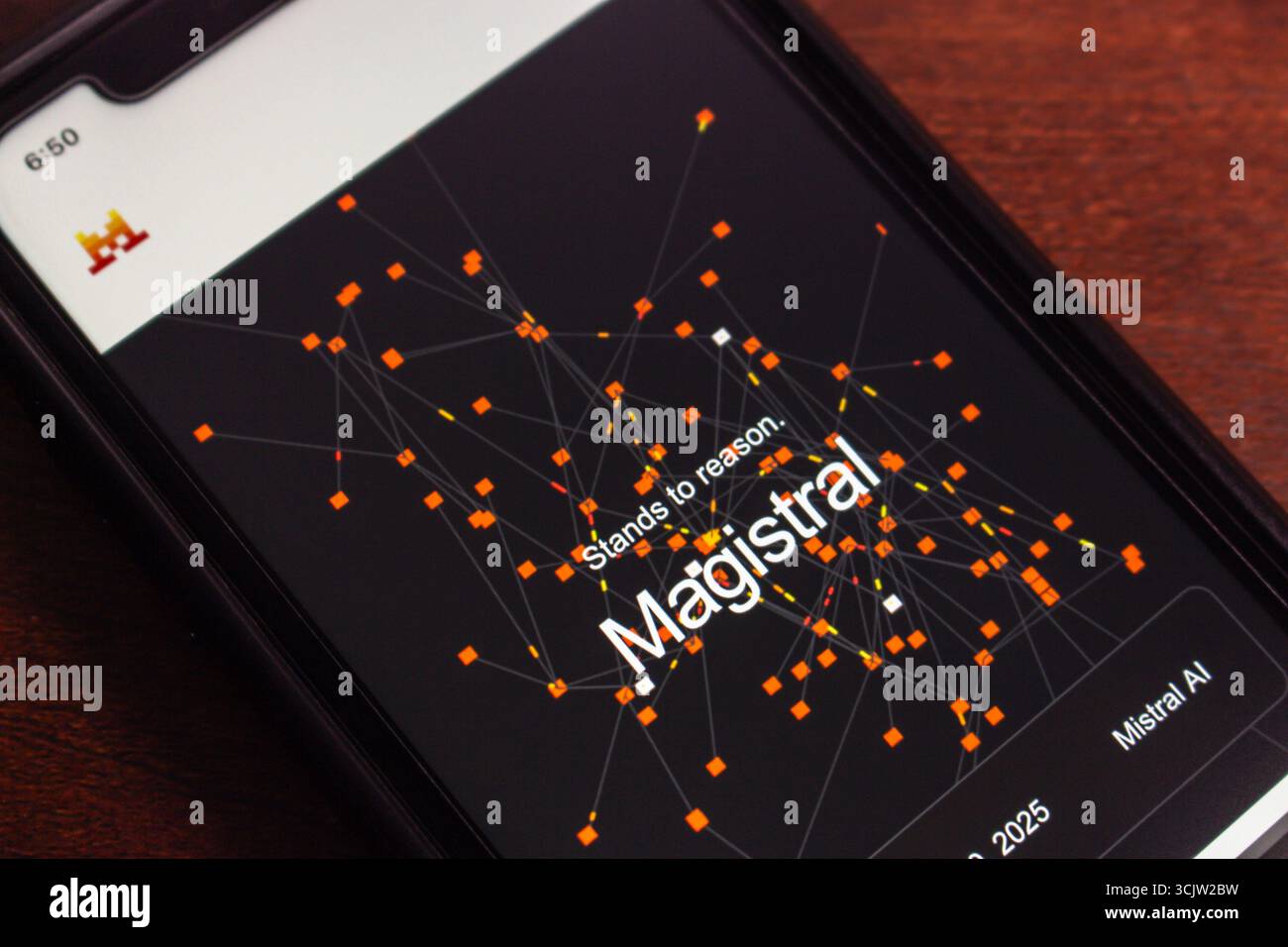 Nahaufnahme eines Smartphones mit der Benutzeroberfläche des Magistral-Modells von Mistral AI mit abstrakter Netzwerkvisualisierung und Branding-Elementen. Stockfoto