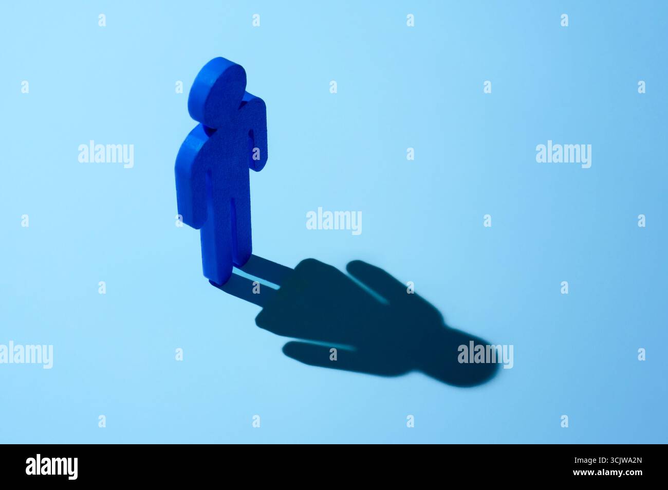 Eine Figur eines Mannes, der einen Schatten einer Frau wirft. Geschlechterdysphorie, Geschlechterkonfusion und Transgender-Konzept. Stockfoto