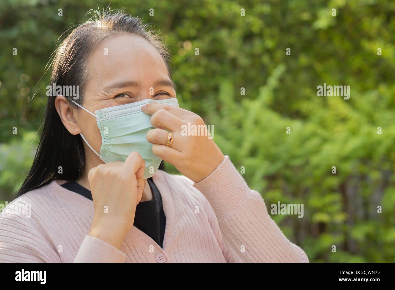 Seitenansicht Porträt der glücklichen asiatischen Frau auf schützende Gesichtsmaske im Freien. Kopierbereich. Gesundes Konzept. Stockfoto