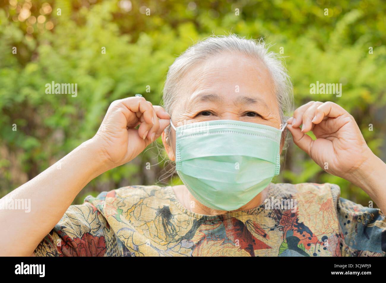 Asiatisches Seniorporträt und Nahaufnahme mit Medizinmaske auf dem Gesicht über Naturhintergrund. Senior Healthy Konzept. Stockfoto