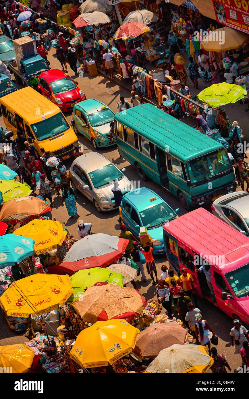 Accra, Ghana - 5. November 2022: Aus der Vogelperspektive auf die belebten Straßen des Makola Markts, ein lebendiger Wandteppich aus farbenfrohen Fahrzeugen, Regenschirmen und die lebendige Energie des Handels. Stockfoto