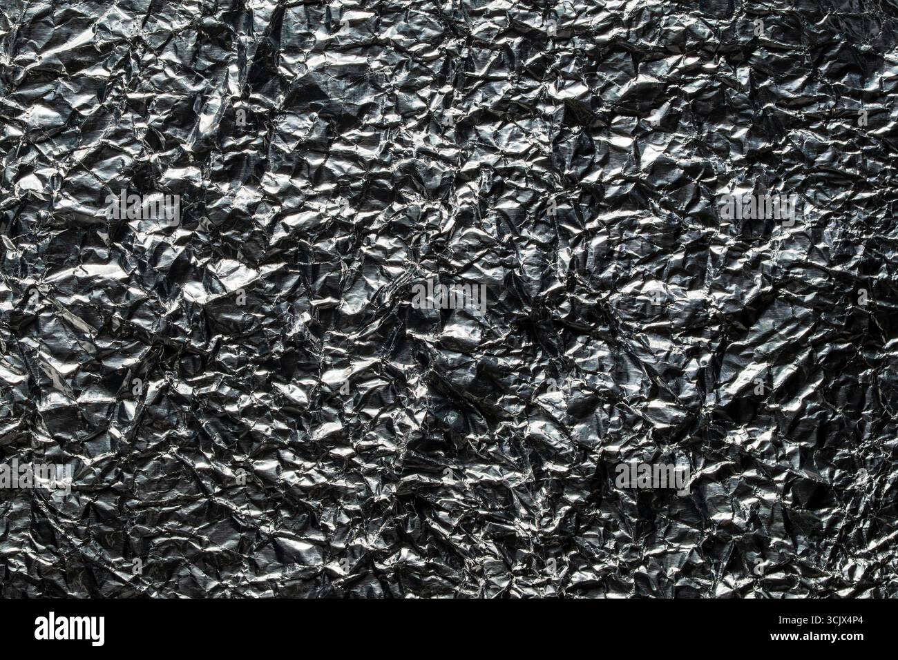 Hintergrund und Textur der gebrauchten zerknitterten Schokoladenfolie, Nahaufnahme, Draufsicht. Glänzende Aluminiumfolie ohne Schokoladenbonbons Stockfoto