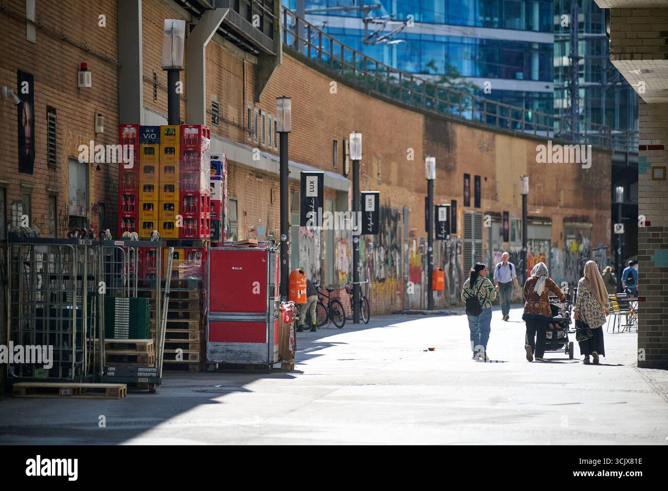 Fußgänger gehen an einer aktiven Baustelle im Stadtzentrum vorbei, Weitwinkelrahmen, dynamische städtische Umgebung, starkes Tageslicht, geeignet für E Stockfoto