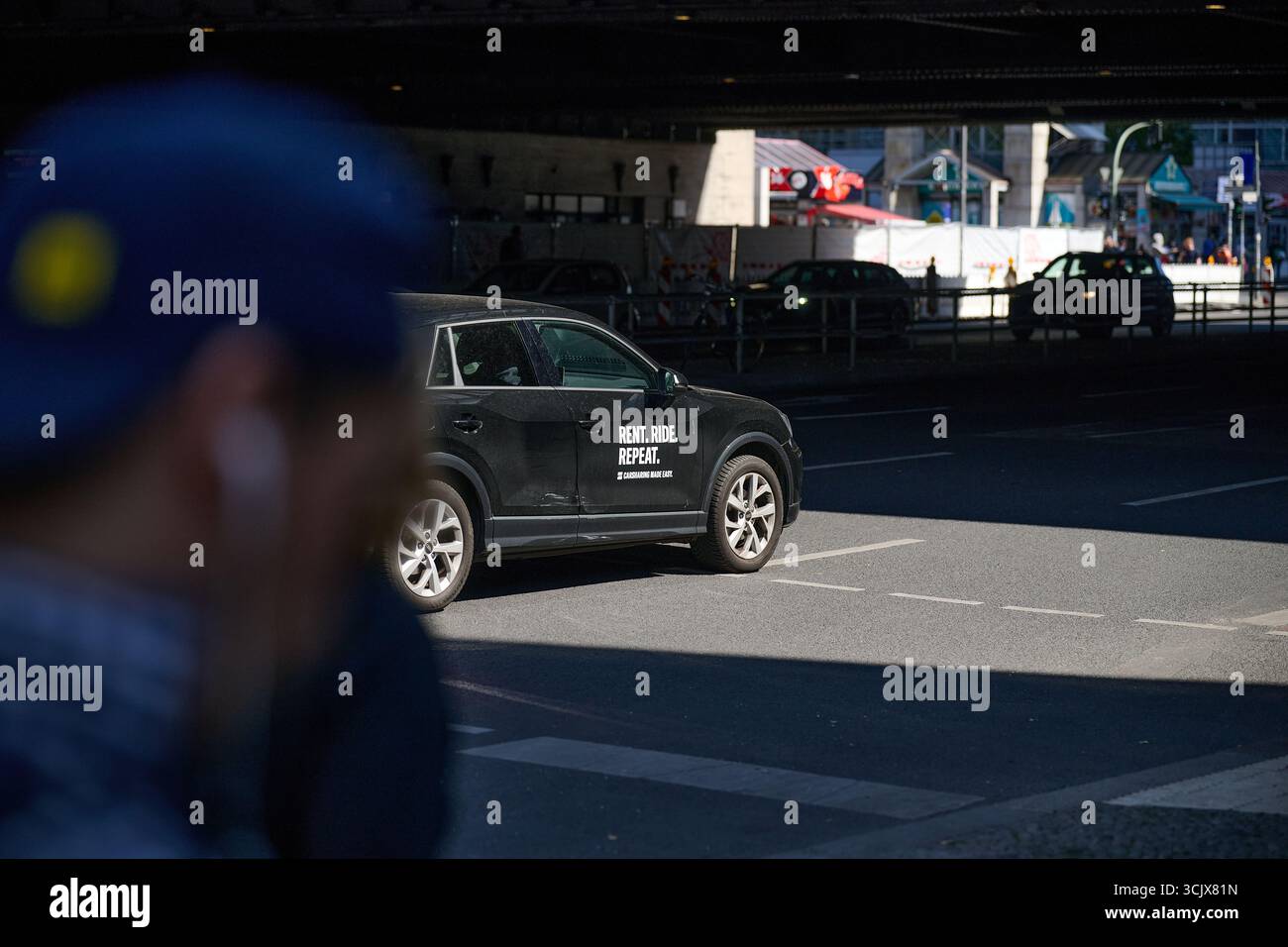 Taxi- und Straßenverkehr unter Stadtbrücke, flaches horizontales Foto, starkes Tageslicht, dynamische Stadtumgebung, kommerzielle Nutzung in Verkehrsmitteln oder Stockfoto