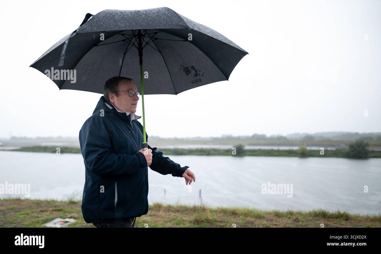Marl, Deutschland. September 2025. Oliver Krischer (Grüne), Umweltminister in Nordrhein-Westfalen, spaziert mit einem Regenschirm entlang der Lippe. Der Bau der neuen Deiche in Höhe von 95 Millionen Euro ist das größte Hochwasserschutzprojekt in Nordrhein-Westfalen. In den letzten neun Jahren wurden die Deiche an der Nordseite der Lippe erneuert. Nun beginnt der letzte Bauabschnitt an einem 500 Meter langen Deich an der Südseite des Flusses. Quelle: Fabian Strauch/dpa/Alamy Live News Stockfoto