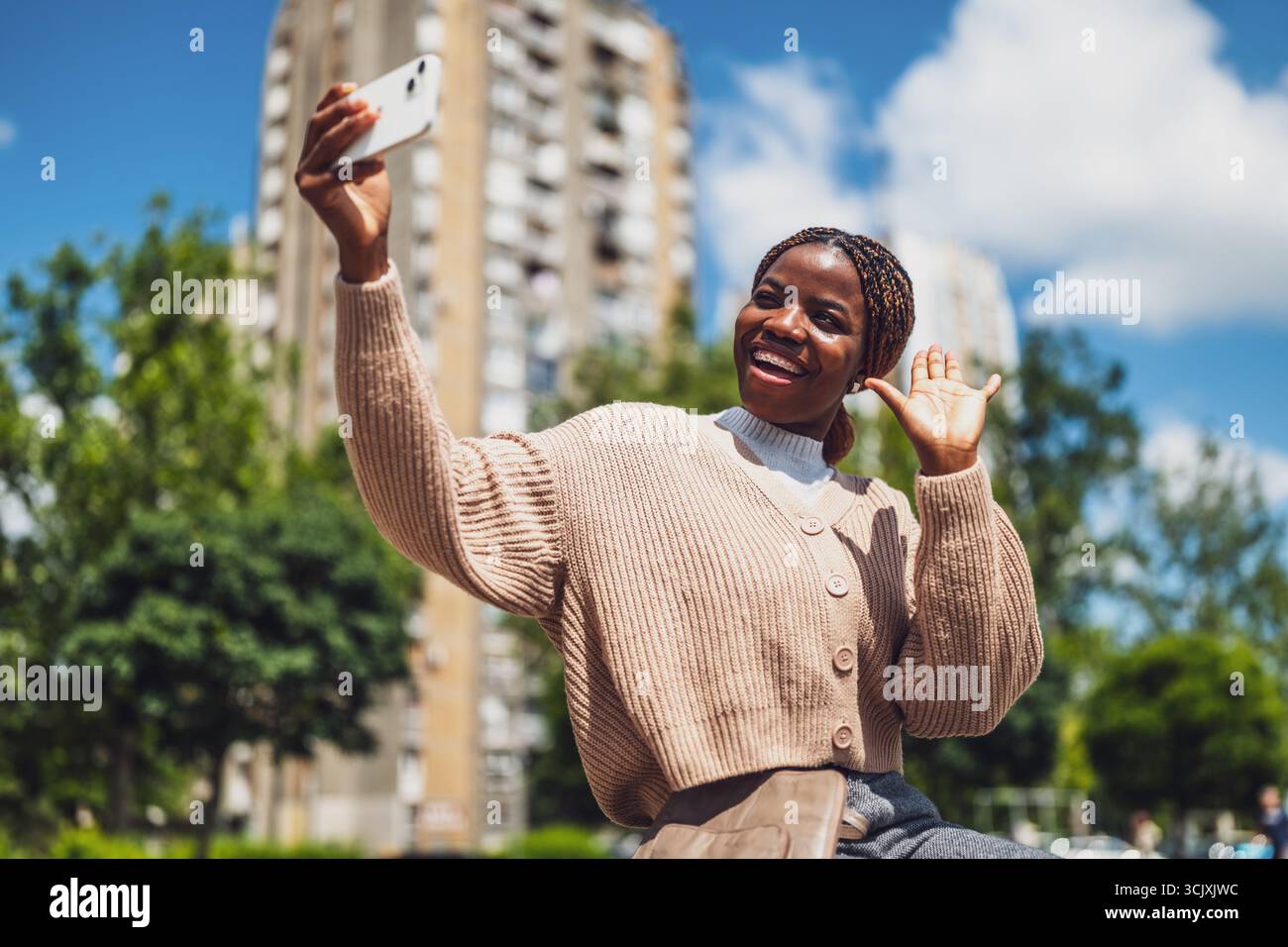 Die junge Happy Black Woman benutzt ein Smartphone. Sie lacht und winkt während eines Videoanrufs. Stockfoto