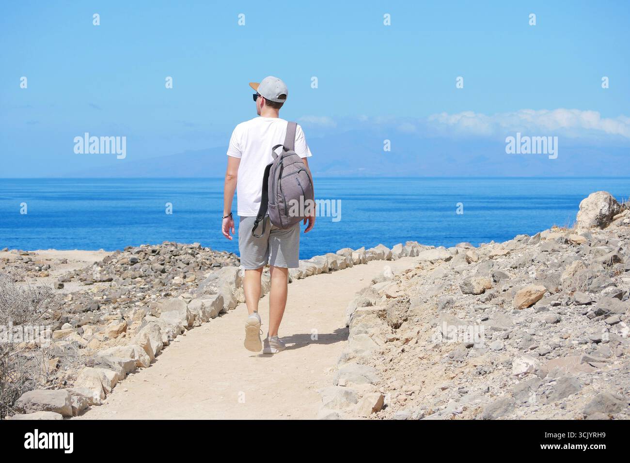 Mann wandert am sonnigen Tag auf dem Coastal Trail in Richtung Meer. Stockfoto