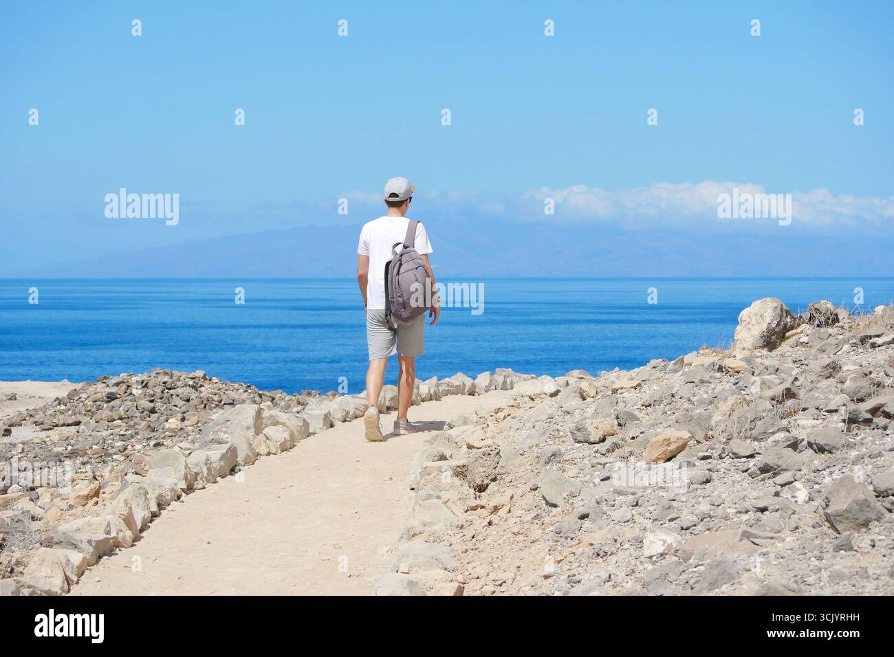 Mann wandert am sonnigen Tag auf dem Coastal Trail in Richtung Meer. Stockfoto