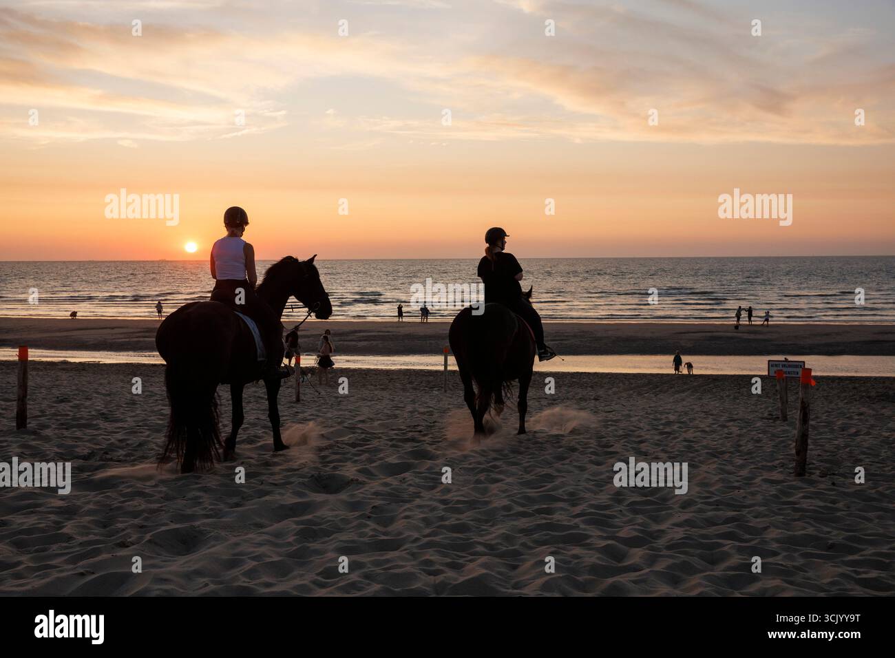 Radfahrer am Strand in Oostkapelle auf der Halbinsel Walcheren, Sonnenuntergang, Zeeland, Niederlande. Reiter am Strand von Oostkapelle auf Walcheren, Sonnenunt Stockfoto