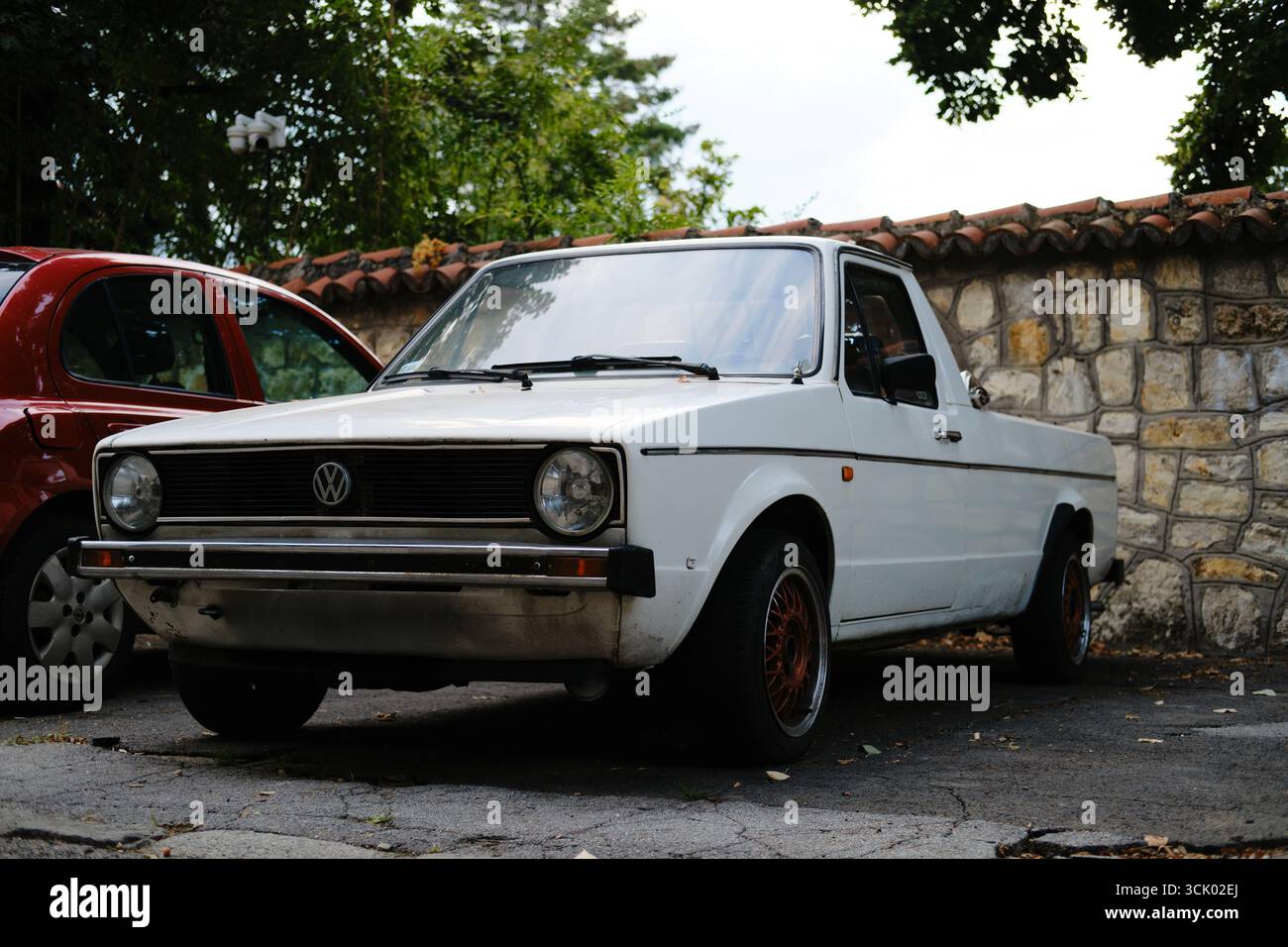 Der alte weiße Volkswagen Pickup parkte auf der Straße in Belgrad in der Nähe von Steinmauern und Bäumen. Belgrad, Serbien - 21. August 2025. Stockfoto