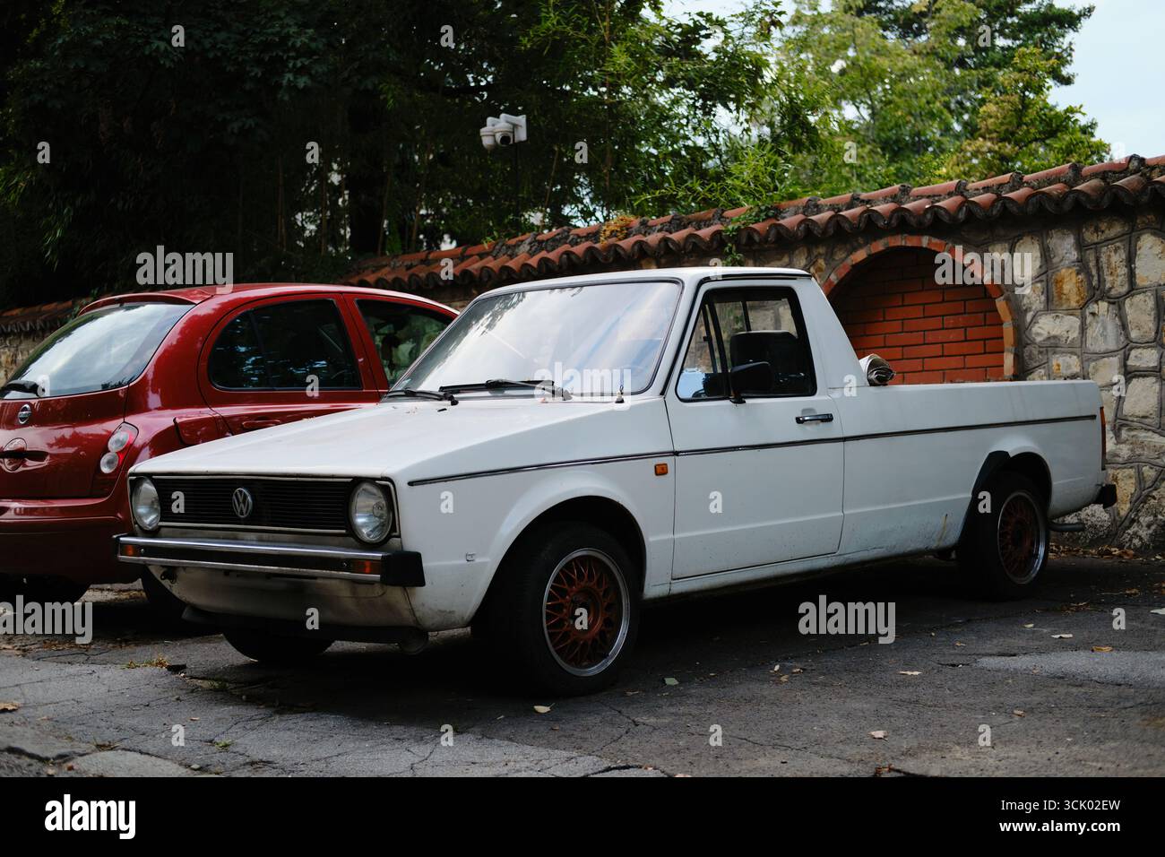 Der alte weiße Volkswagen Pickup parkte auf der Straße in Belgrad in der Nähe von Steinmauern und Bäumen. Belgrad, Serbien - 21. August 2025. Stockfoto