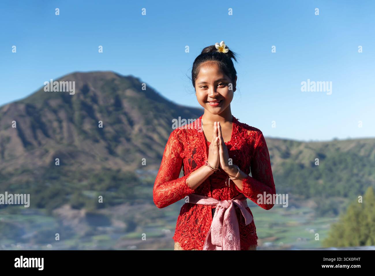 Porträt der balinesischen Frau mit Händen umschlossene Willkommensgeste mit Mt. Batur-Ansicht Stockfoto