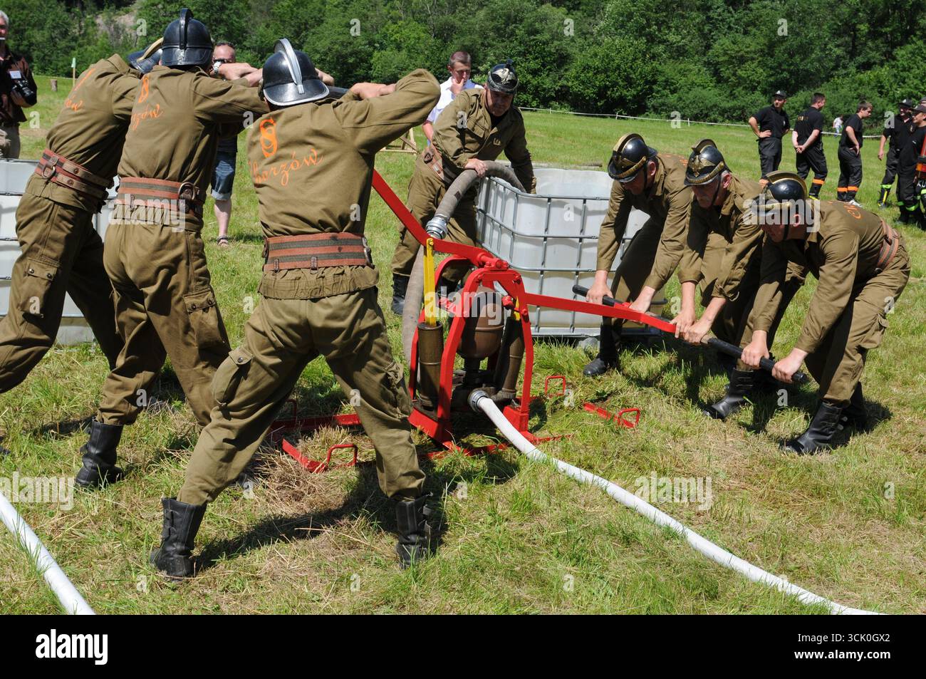 Feuerwehrleute in historischen Uniformen, die während des Feuerwehrwettbewerbs manuelle Pumpe betreiben, Rudawka Rymanowska, Subkarpaten, Polen Stockfoto