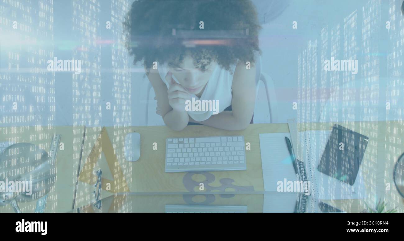 Lehnende Frau, die mit Maus, Tablet, Notebook, Stift, Mesh-Organizer auf die Tastatur am Schreibtisch blickt Stockfoto