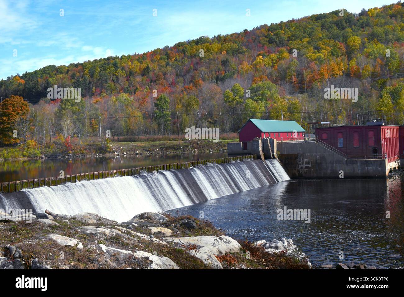 Der Androscoggin River in New Hampshire fließt über den Cross Power Dam in New Hampshire. White Mountains und Herbstlaub sind hinter der Pflanze. Stockfoto