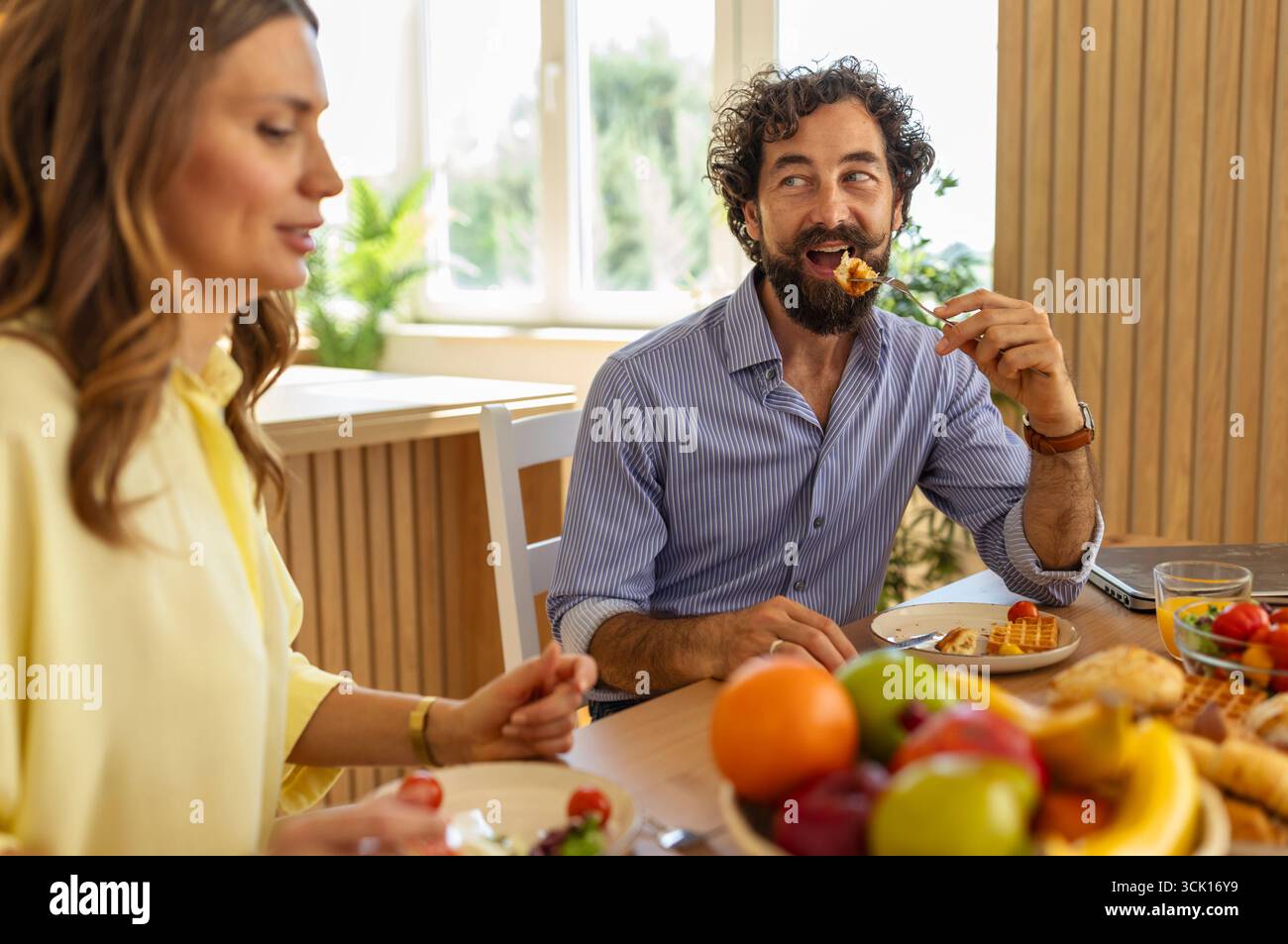 Mann und Frau haben ein nahrhaftes Frühstück mit Früchten und gemeinsame Gespräche in sonniger und einladender Atmosphäre Stockfoto