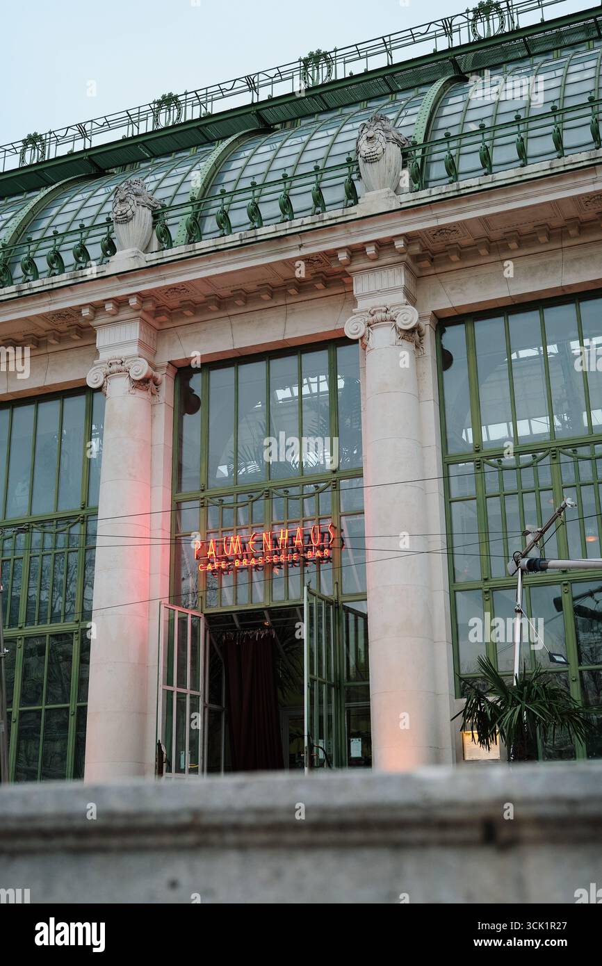 Fassade des berühmten Palmhause Cafés in Wien mit Neonschild, antiken Säulen und großen Fenstern mit grünen Rahmen der Orangerie. Stockfoto