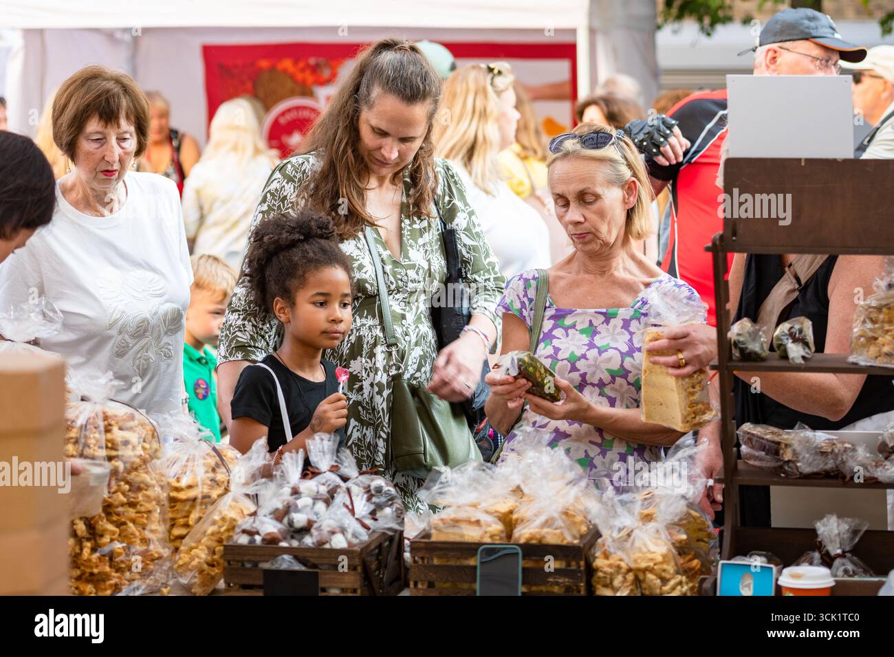 Eine multirassische Familie mit Großmutter, Mutter und Tochter, die Süßigkeiten auf einem Street Food and Craft Markt in Vilnius, Litauen, Europa kaufen Stockfoto
