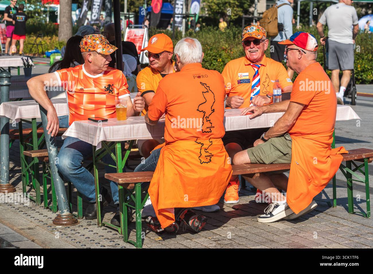 Eine Gruppe holländischer Fußballfans in oranger Kleidung saß zusammen und trank vor dem Spiel an einem Tisch im Freien in einem öffentlichen Bereich Stockfoto