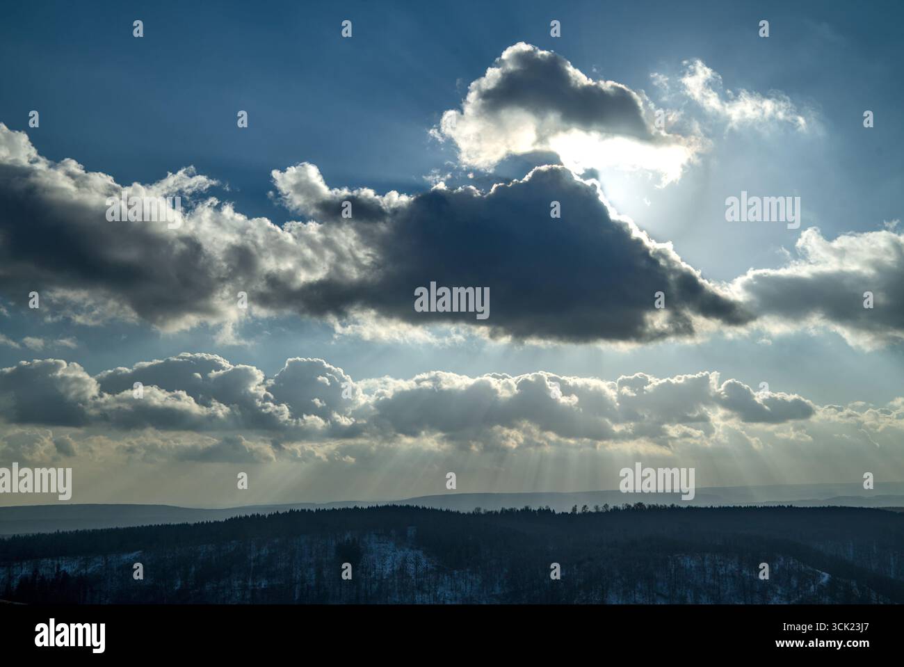 Landschaft, die vom Himmel dominiert wird, mit Sonne hinter einer Wolke und Sonnenstrahlen, die durchströmen. Stockfoto