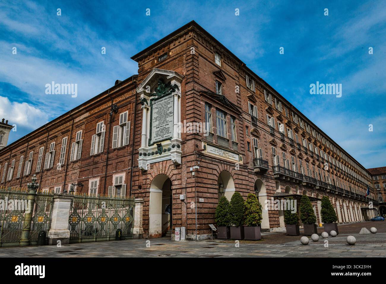 Eine Weitwinkelaufnahme der Biblioteca reale auf der Piazza Castello, Turin. Das Foto zeigt die kunstvolle Barockarchitektur vor einem markanten Himmel. Stockfoto
