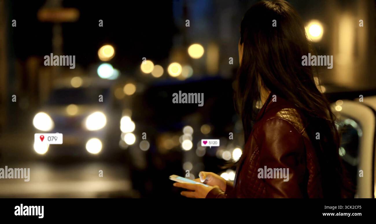 Telefon überprüfen asiatische Frau, die nachts rote Jacke auf dem Bürgersteig trägt, mit Autoscheinwerfern, Kopierraum Stockfoto
