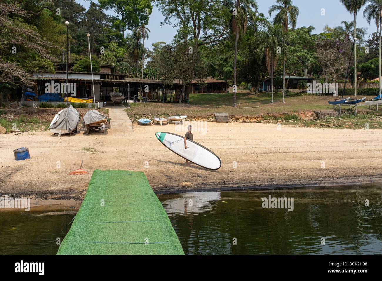 54-jähriger brasilianischer Mann am Rand des Guarapiranga-Damms mit Stand-up-Paddleboard. Stockfoto