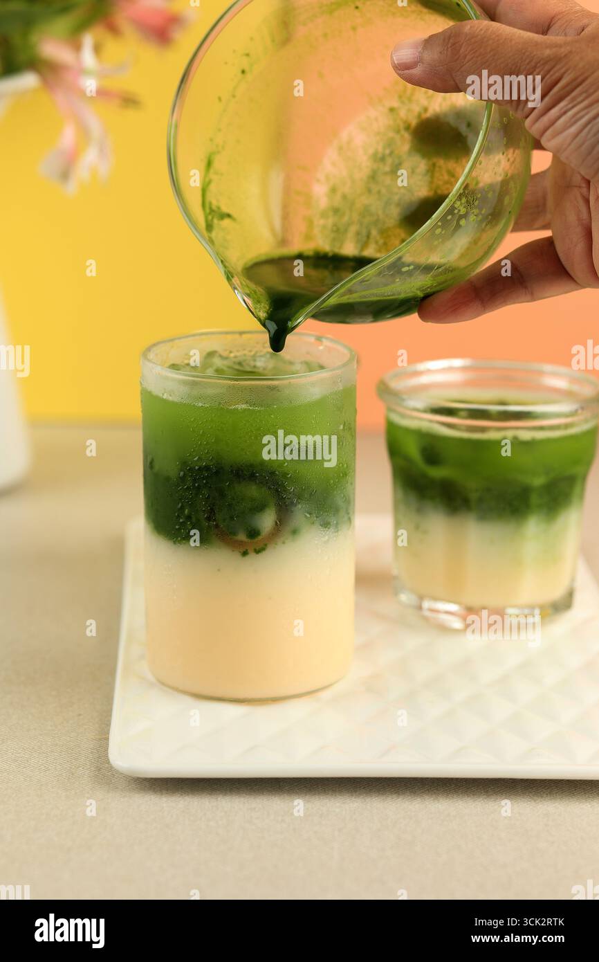 Gießen von Matcha in den Milchprozess Herstellung von Matcha Latte, virales japanisches Getränk Stockfoto