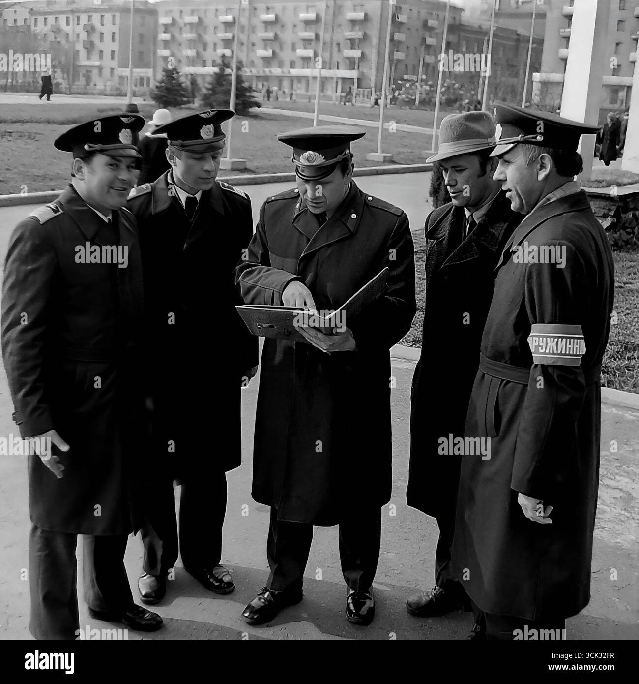 Der Kommandeur einer freiwilligen Volksdruschina (DND)-Patrouille führt in den 1980er Jahren einen Rostercheck mit seiner Gruppe auf einem Platz in Slowiansk, ukrainische SSR, durch Das Archivfoto zeigt ein gemischtes Team der Druzhina, darunter Mitarbeiter in Abteilungsuniformen und Freiwillige mit dem charakteristischen „Druzhinnik“-Armband. Diese Szene spiegelt den organisierten Charakter der Arbeit der DND bei der Aufrechterhaltung der öffentlichen Ordnung in sowjetischen Städten und den Geist der kollektiven Verantwortung in der späten UdSSR-Ära wider Stockfoto