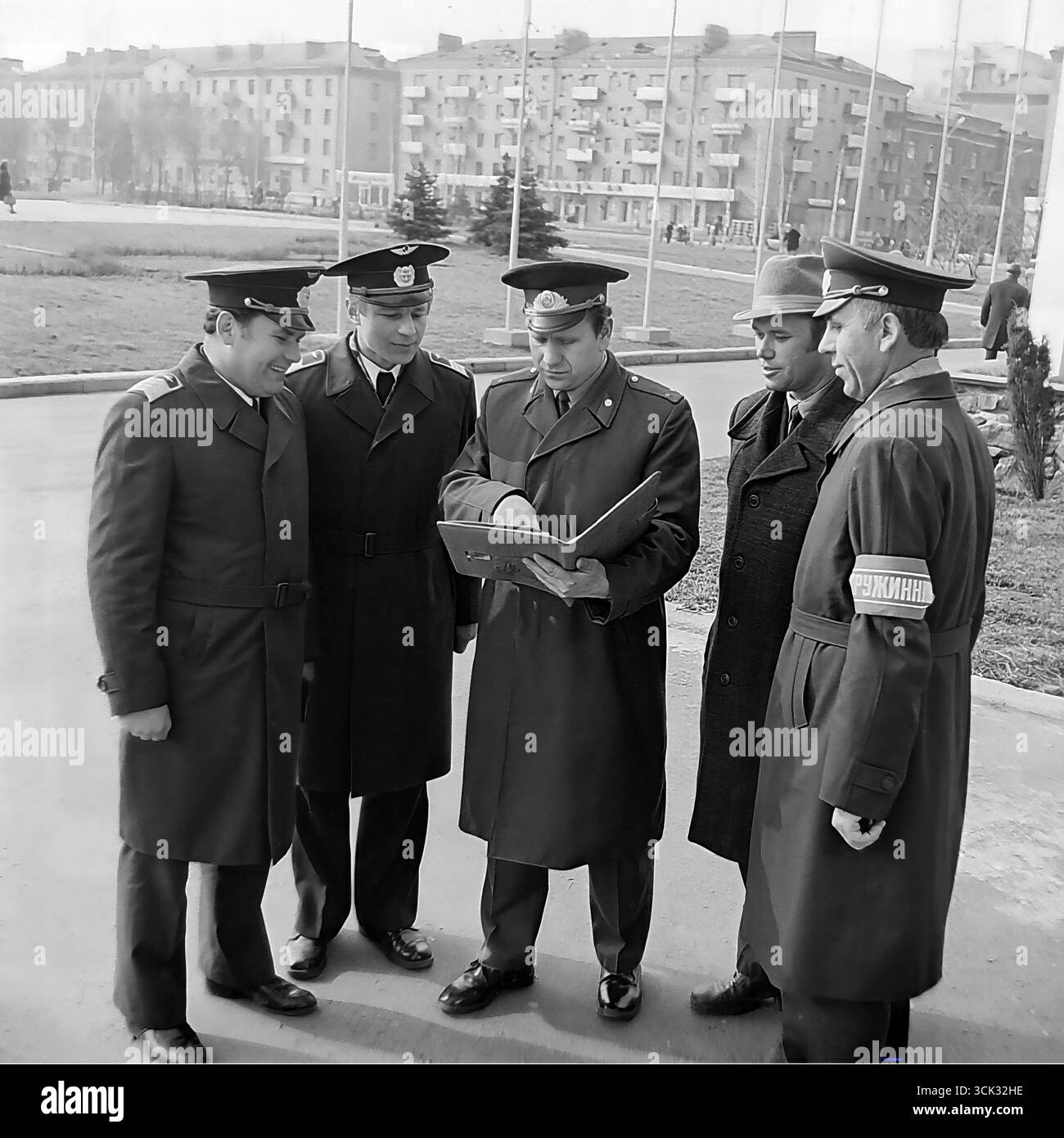 Der Leiter des Freiwilligen Zentrums der Volksdruschina (DND) führt in den 1980er Jahren ein Briefing oder eine Rosterkontrolle mit einer Patrouillengruppe auf einem Platz in Slowiansk, ukrainische SSR, durch Das Archivfoto zeigt ein gemischtes Team der Druzhina, darunter Angestellte in Uniformen der Abteilung und Freiwillige, von denen einer das charakteristische „Druzhinnik“-Armband trägt. Diese Szene spiegelt den organisierten Charakter der Arbeit der DND bei der Aufrechterhaltung der öffentlichen Ordnung in sowjetischen Städten und den Geist der kollektiven Verantwortung wider Stockfoto